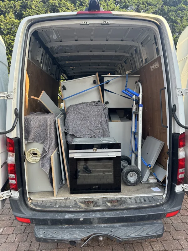 Household furniture and a moving trolley loaded in the rear of a van